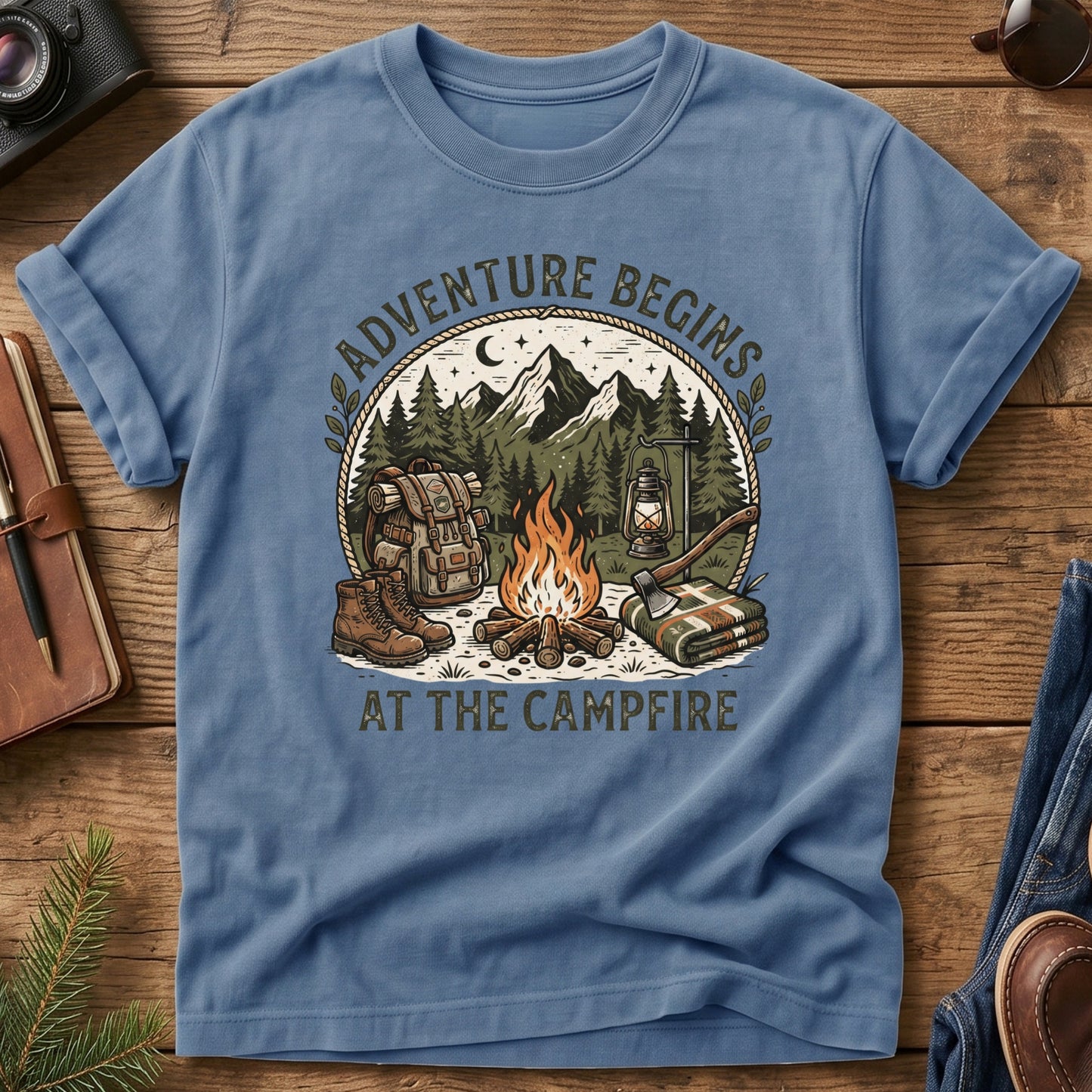Adventure Begins Tee – Blue Jean flat lay, campfire badge graphic