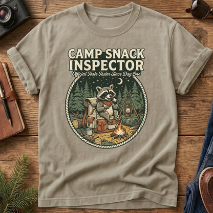 Camp Snack Inspector Tee – styled flat lay, raccoon campfire graphic