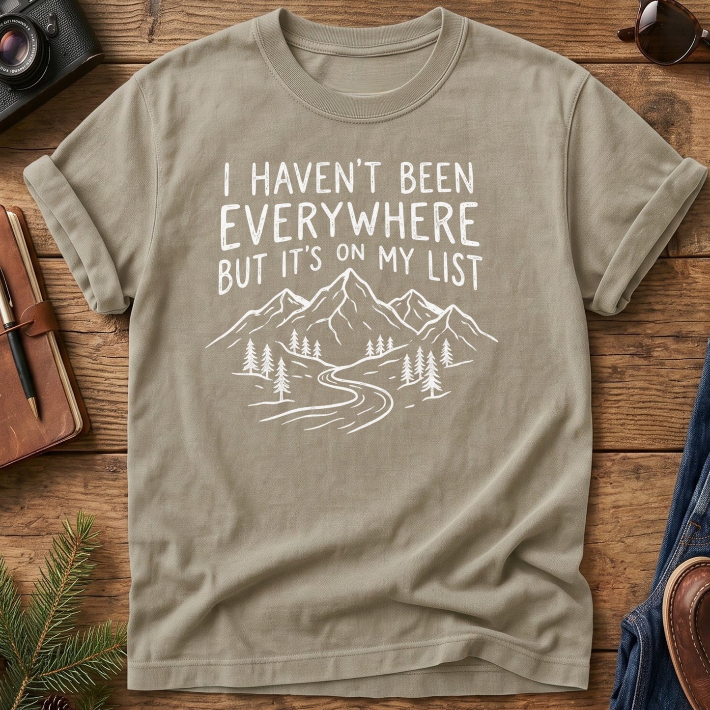 I Haven't Been Everywhere Tee in Khaki — mountain and river wanderlust graphic with hand lettering