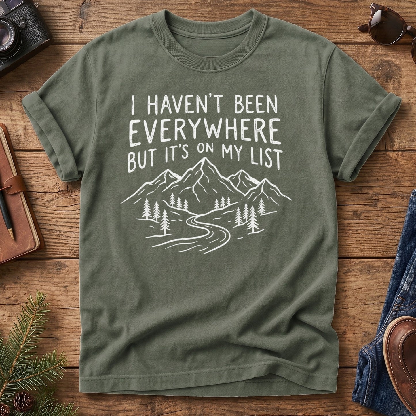 I Haven't Been Everywhere Tee in Moss — mountain and river wanderlust graphic with hand lettering