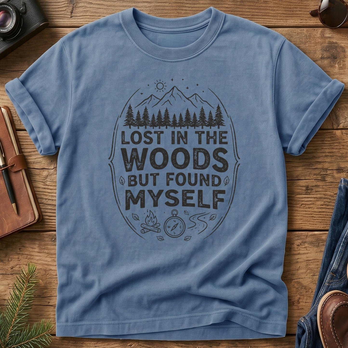 Lost In The Woods But Found Myself Tee in Blue Jean — camp badge graphic with compass and campfire