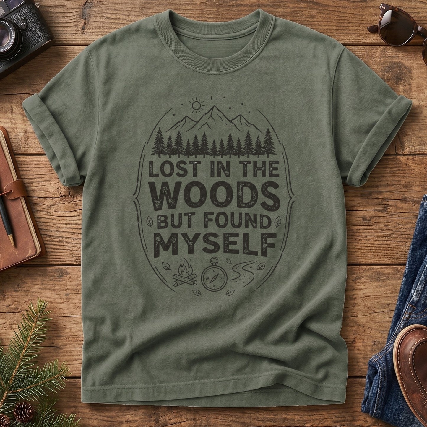 Lost In The Woods But Found Myself Tee in Moss — camp badge graphic with compass and campfire