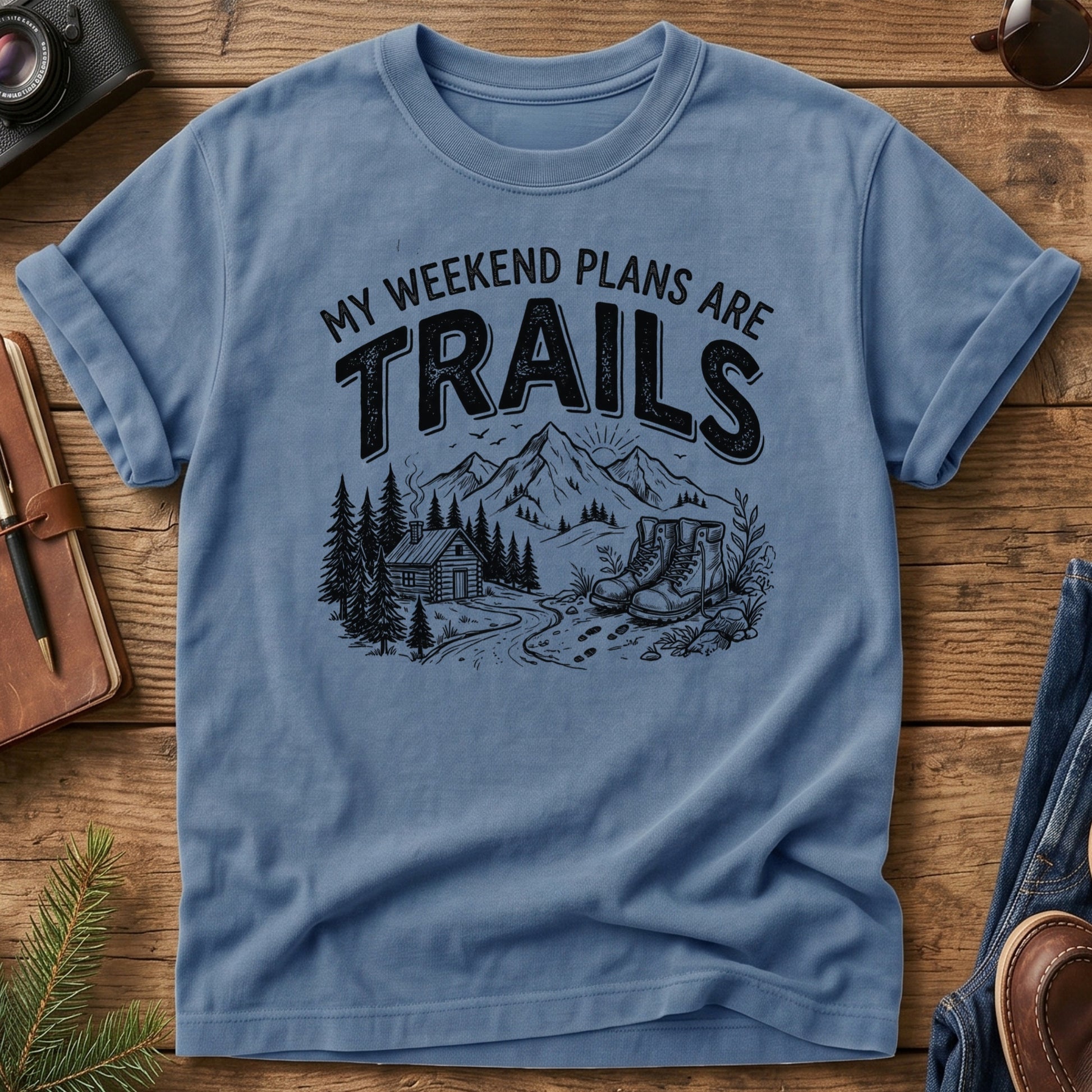 My Weekend Plans Are Trails Tee in Blue Jean — cabin, mountain, and hiking boots graphic