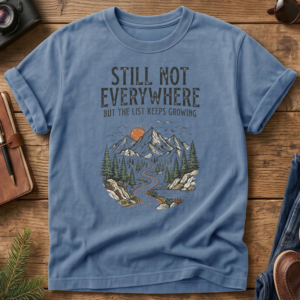 Still Not Everywhere Tee – mountain river valley sunrise graphic on Comfort Colors 1717 tee, flat lay