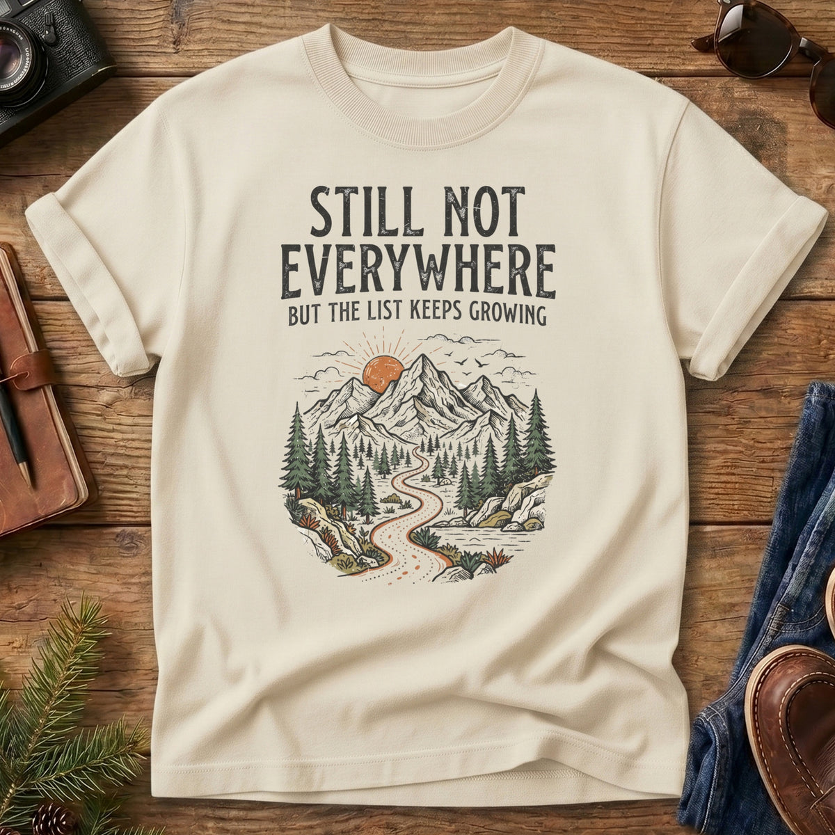 Still Not Everywhere Tee – mountain river valley sunrise graphic on Comfort Colors 1717 tee, flat lay