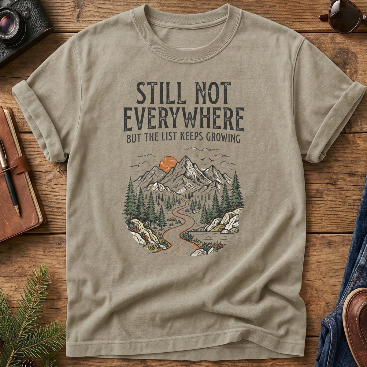 Still Not Everywhere Tee – mountain river valley sunrise graphic on Comfort Colors 1717 tee, flat lay